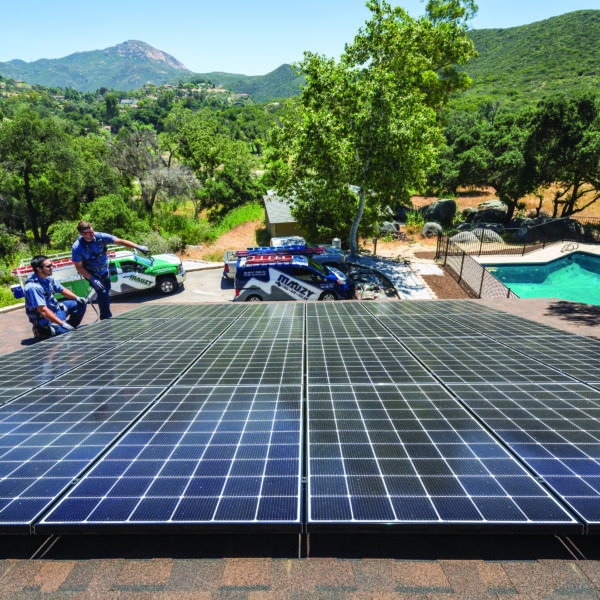 Two Mauzy technicians standing on a roof pointing to a solar installation