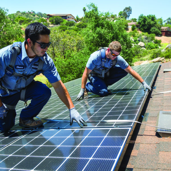 Two Mauzy technicians installing solar panels on the roof of a customer's home