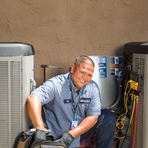 mauzy technician crouching next to air conditioning units doing maintenance