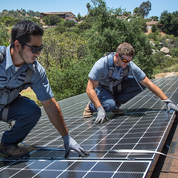 Two Mauzy technicians installing solar panels on the roof of a customer's home